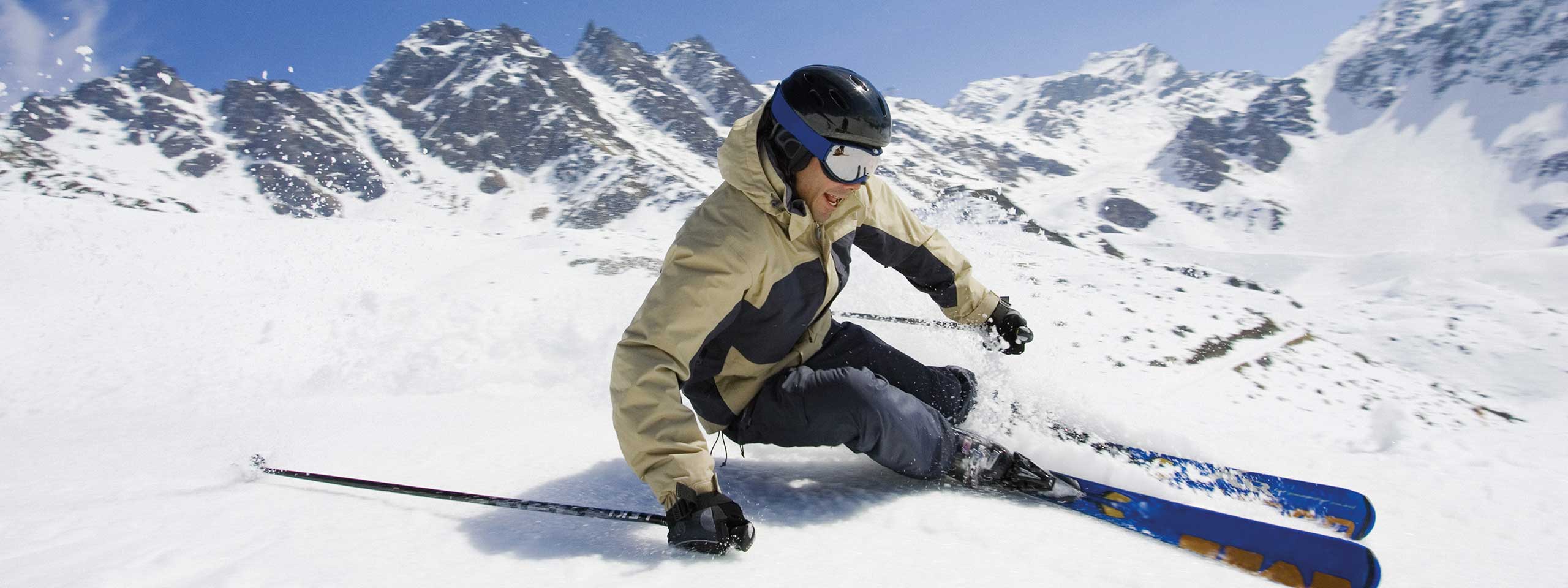 Skifahrer mit Sportbrille im Schnee fährt einen Abhang runter